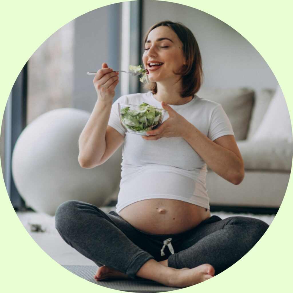 Mulher grávida jovem comendo salada em casa